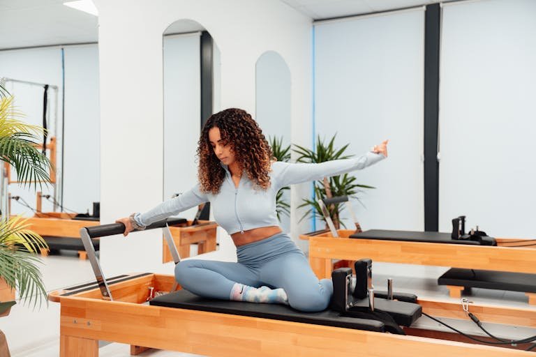 A woman exercising on a reformer in a pilates studio, embodying a healthy lifestyle.