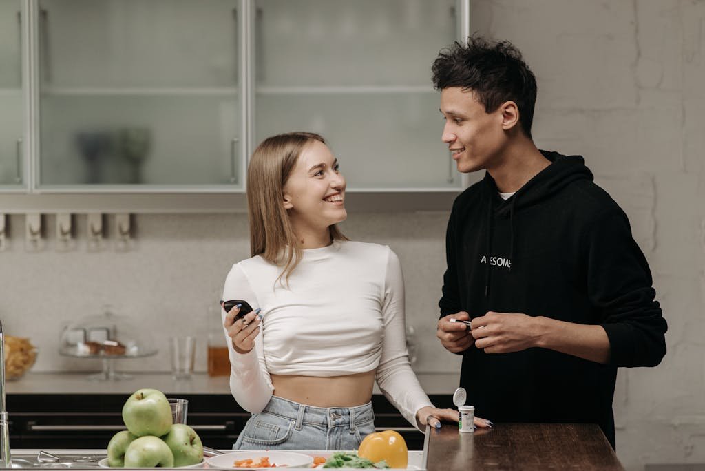 Smiling couple checking blood sugar with glucometer in kitchen.