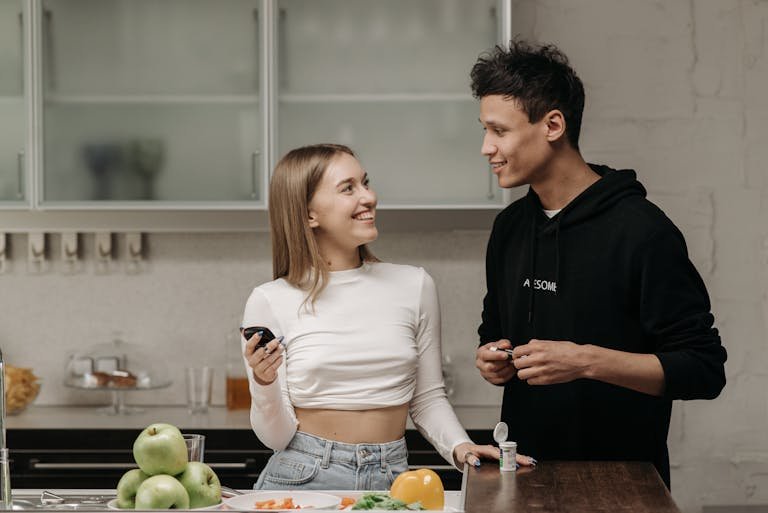 Smiling couple checking blood sugar with glucometer in kitchen.